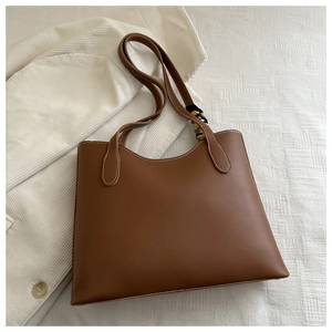Détail d'un sac cabas marron en cuir avec foulard en soie décoratif et surpiqûres blanches