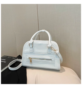 Close-up of white lychee texture leather Boston bag with elegant golden zipper detail