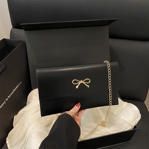 Elegant black leather envelope bag with gold bow clasp and delicate chain strap