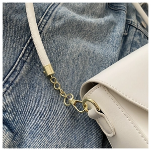 Détail des crochets en métal doré et de la chaîne sur un sac à main blanc