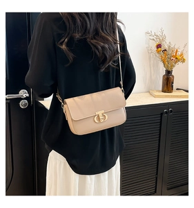 Detail of beige crossbody bag with gold CD buckle worn by a model in modern setting