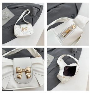 Detail view of white PU leather shoulder bag featuring gold bow accent and zip closure