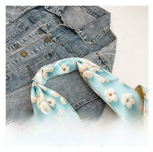 Close-up of wide light blue shoulder strap with 3D white floral embroidery patterns