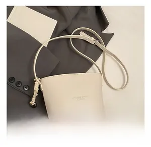 Close-up of beige pebble texture bucket bag with knot shoulder strap on blazer