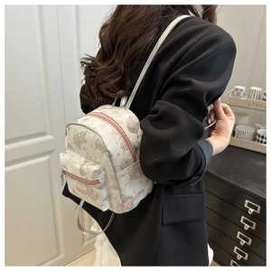 Mini cream backpack featuring pink butterfly prints and slender silver shoulder straps