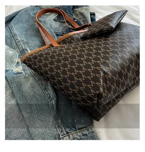 Détail de la texture monogramme en similicuir marron et d'une petite pochette zippée assortie