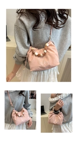 Detailed macro view of pink pleated handbag with chic beaded handle and long strap