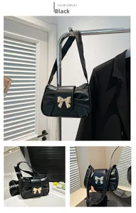 Detail of black pleated shoulder bag featuring a decorative gold metal bow accent