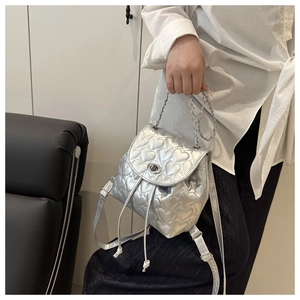Macro detail of silver heart-quilted mini backpack with metal chain handle and twist lock