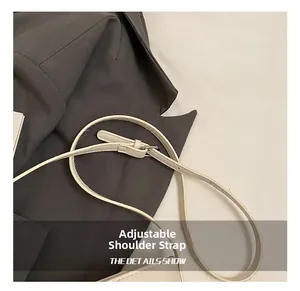 Detail of adjustable beige leather shoulder strap with silver metal buckle hardware