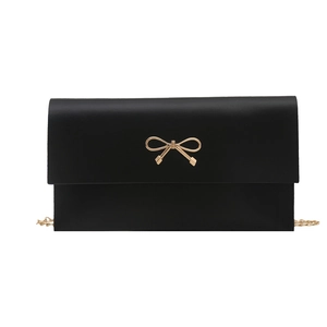 Minimalist black matte crossbody bag with golden bow clasp and metal chain strap