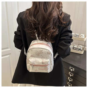 Detail of a white butterfly print mini backpack with pink zipper on black blazer