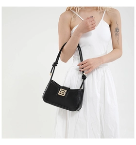 Detail of a black leather shoulder bag with a gold geometric buckle and knotted strap