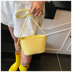 Detail of yellow lychee pattern bucket bag featuring knotted drawstring and metal sphere charm