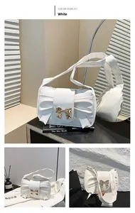 Close-up of white pleated shoulder bag featuring a gold metal bow buckle and elegant texture