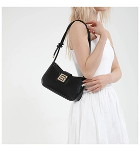 Detail of black baguette bag featuring large gold buckle and twisted shoulder strap design