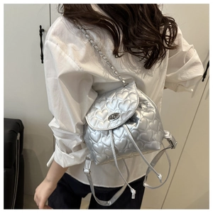 Silver quilted heart backpack with metallic chain straps shown on a model's back