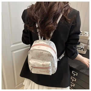 Close-up of mini backpack with butterfly patterns and pink zippers shown on a model