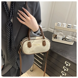 Detail of a cream canvas handbag with dark brown leather trim and gold metal hardware