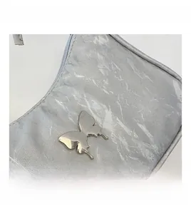 Macro detail of silver pleated fabric and stylish metallic butterfly buckle on a shoulder bag