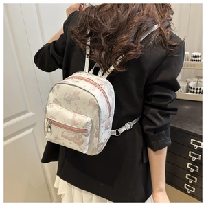 Close-up of pink butterfly prints and mini leather details on the white backpack