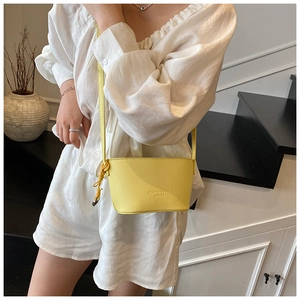 Detail of yellow lychee leather crossbody bag featuring embossed fashion text branding
