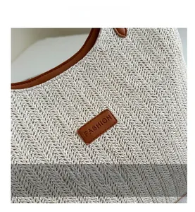 Detail of hand-woven beige straw bag featuring brown leather trim and fashion logo patch