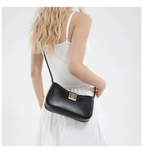 Detail of elegant black leather shoulder bag with a rectangular golden buckle on white dress