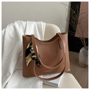 Brown leather tote bag featuring white contrast stitching and silk scarf on white blazer