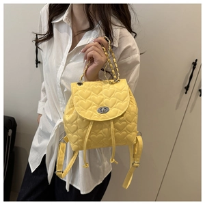 Detail of yellow heart-quilted mini backpack with silver twist lock and chain handle