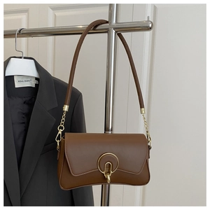 Détail du sac sous le bras en cuir marron vintage avec boucle dorée et bandoulière chaîne
