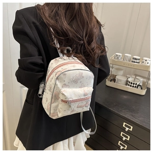 Detail of mini cream backpack with butterfly print on a model in a cozy room