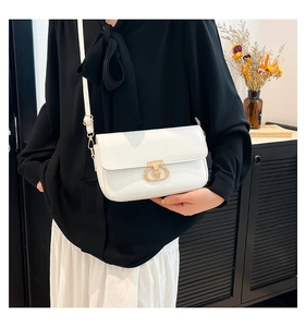 Detail of white leather crossbody bag with elegant gold metal buckle worn by model