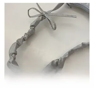 Detail of silver pleated shoulder strap with a decorative bow on a fashion handbag
