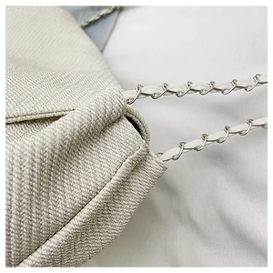 Macro shot of beige woven fabric texture and intertwined silver chain leather strap