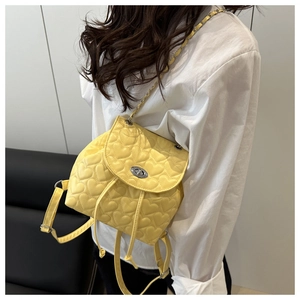 Detail of lemon yellow quilted heart backpack with silver metal twist lock and chain strap