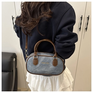Detail of vintage denim Boston bag with brown faux leather handles and golden hardware