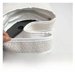 Detailed view of the woven synthetic leather texture and shoulder strap on white bucket bag