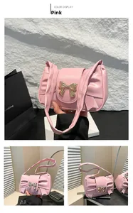 Pink French baguette bag detail with golden bow buckle and ruched strap design