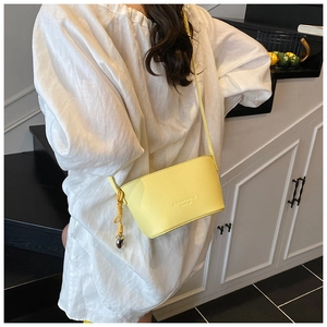 Close-up of yellow lychee pattern crossbody bag with heart pendant and embossed text