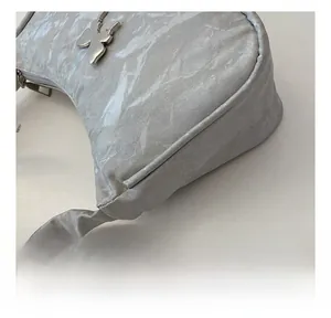 Detail of silver crescent underarm bag with metallic pleated fabric and butterfly charm