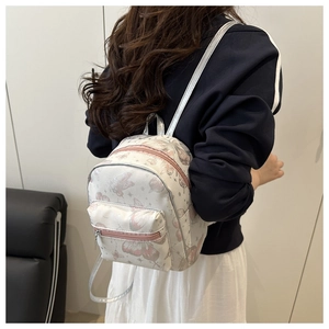 Detail view of the butterfly print on a white PU leather backpack worn by a model