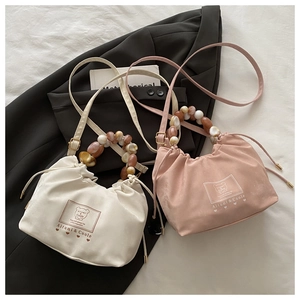 Détail de la poignée en perles et sac nuage à cordon en crème et rose tendre
