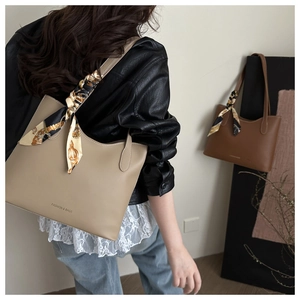 Detail of solid color tote bag with decorative silk scarf and fashion text logo