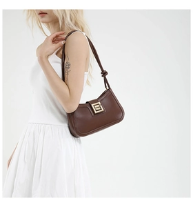 Detail of a dark brown faux leather underarm bag with a golden metal buckle for women