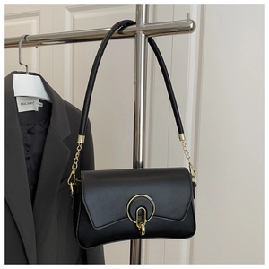 Détail d'un sac à main en cuir noir avec boucle dorée ronde et fine bandoulière