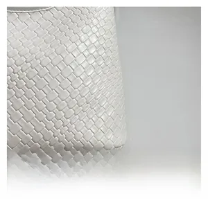 Macro shot of white woven leather texture and cross-stitch detail on bucket bag