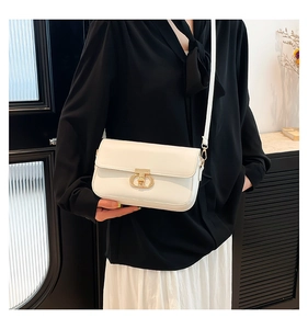 White faux leather crossbody bag with elegant gold oval buckle shown on a model