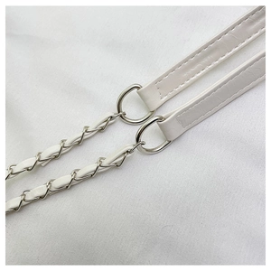 Close-up of white leather tote shoulder strap with silver metal rings and woven chain