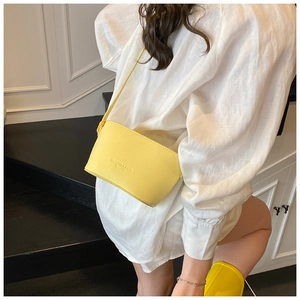 Close-up of yellow leather crossbody bag featuring embossed text and fine litchi texture